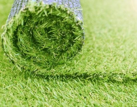 Artificial turf roll. Synthetic grass lawn laying background.